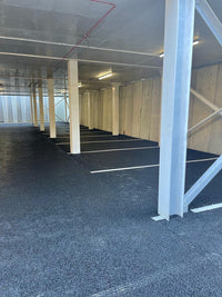 Underground parking garage with concrete floor and white pillars