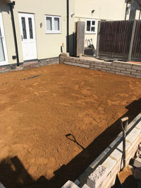 Dirt foundation being prepared for a building project in front of a house.