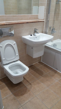 Bathroom with white toilet and sink against tiled walls