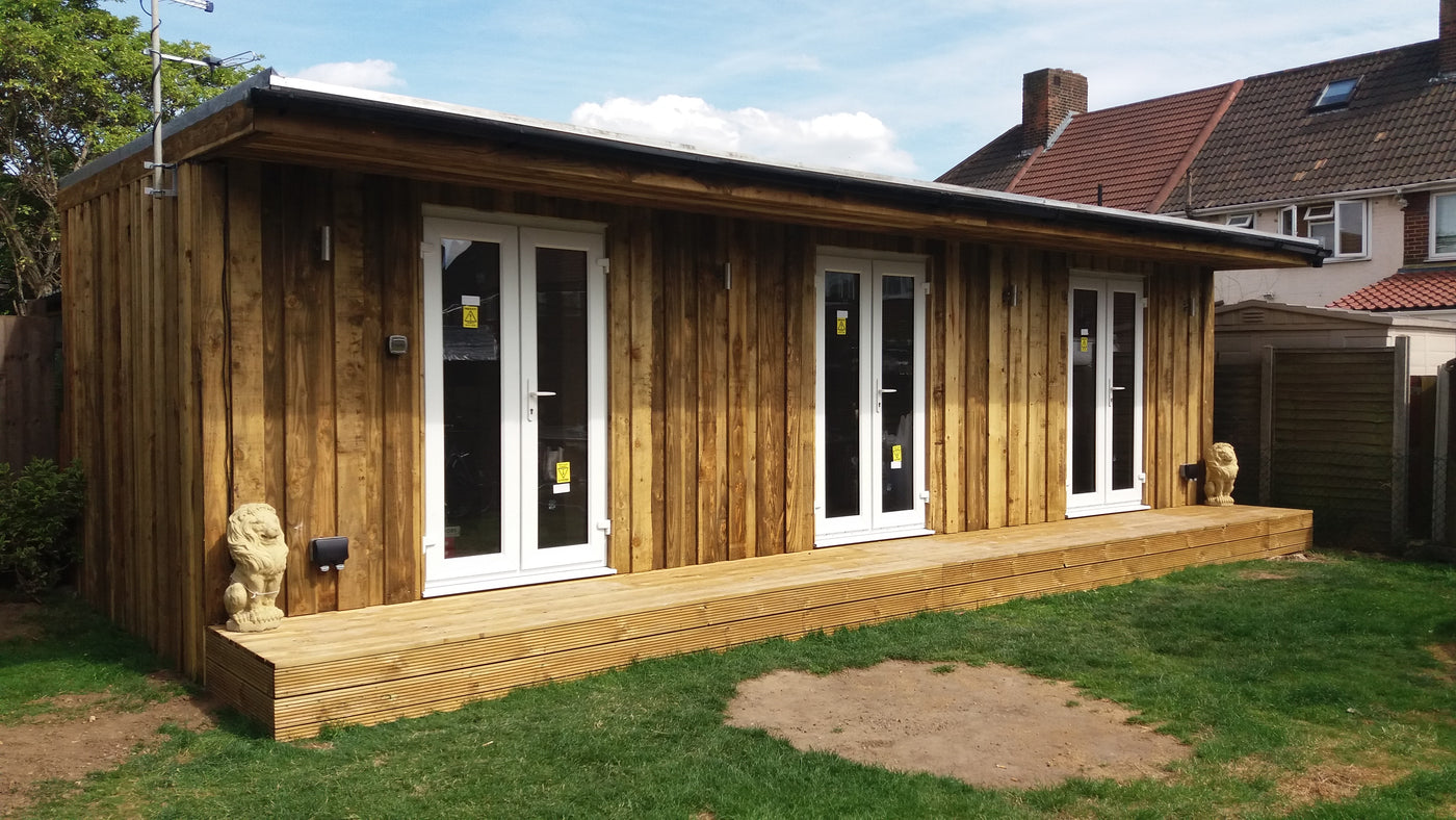 Wooden garden room with glass doors and windows on a grassy area.