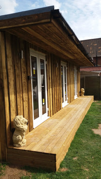 Wooden deck with a railing and two bags on a grassy area