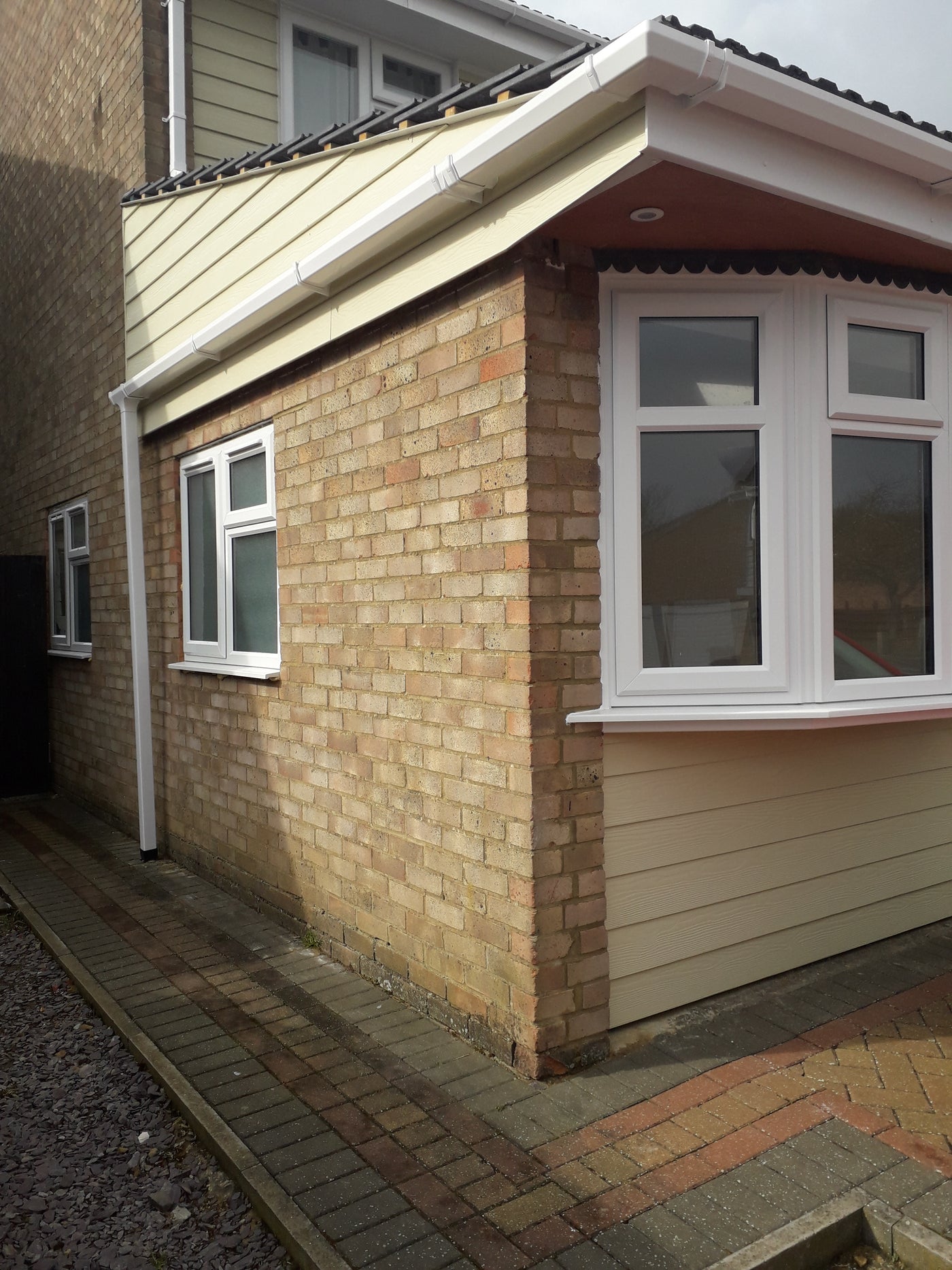 Exterior of a house with brick and siding, featuring windows.