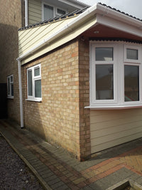 Exterior of a house with brick and siding, featuring windows.
