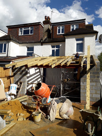 Construction site with a crane and building materials against a blue sky.