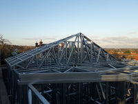 Construction site with a metal roof framework against a clear sky.