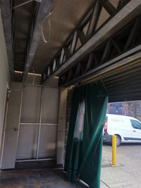 Green curtain hanging from a structure with a white van parked outside.