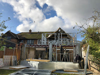 House under construction with metal framework against a blue sky with clouds