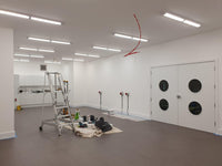 Empty room with white walls, gray floor, and a ladder against a wall.
