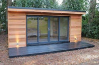 Modern garden office with wooden exterior and glass doors in a forest setting