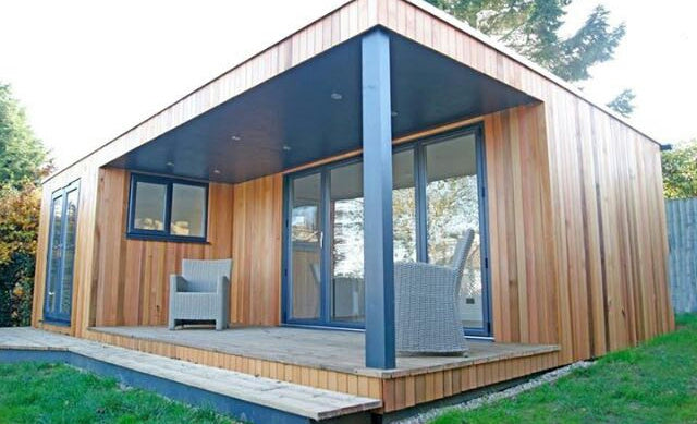 Modern wooden cabin with a deck and chairs in a natural setting