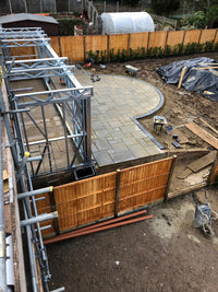 Construction site with metal framework and wooden fence in a backyard setting