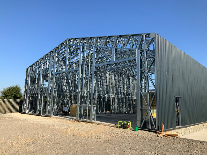 Large metal building under construction with a clear blue sky.