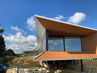 Modern architectural structure with wooden and glass design under a blue sky.