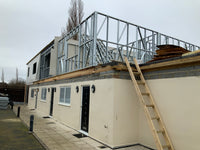 Building under construction with a ladder against a beige exterior wall.