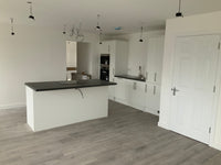 Modern kitchen with white cabinets, black countertops, and gray flooring.
