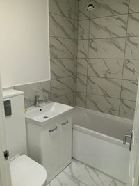 Bathroom with white tiles, sink, and mirror.