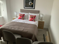 Modern bedroom with a bed, floral pillows, and side tables.