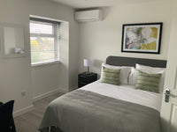 Modern bedroom with a bed, nightstand, lamp, and wall art.