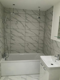 Bathroom with tiled walls and a sink.