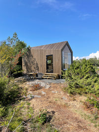 Small wooden cabin in a forested area with clear blue sky