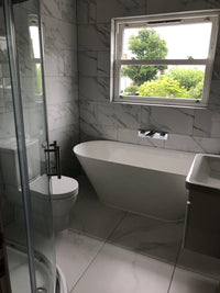 Modern bathroom with a freestanding bathtub, tiled walls, and a window.