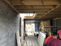 Underconstruction interior with exposed wooden beams and unfinished walls.