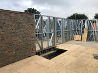 Construction site with metal frame and stone wall