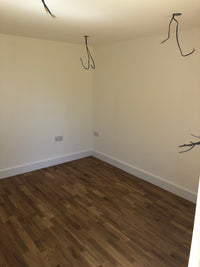 Corner of a room with white walls and a wooden floor.