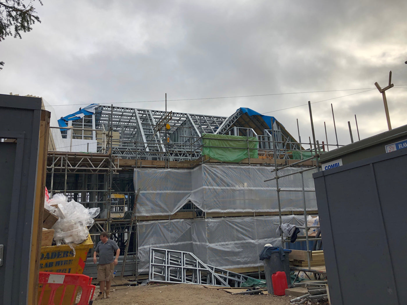 Construction site with scaffolding and building materials under a cloudy sky