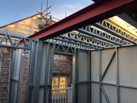 Structural steel framework of a building under construction with brick walls.