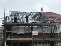 Construction site with scaffolding and workers on a house roof.