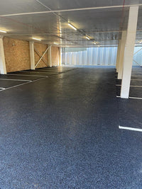 Empty indoor parking garage with a dark floor and white walls.