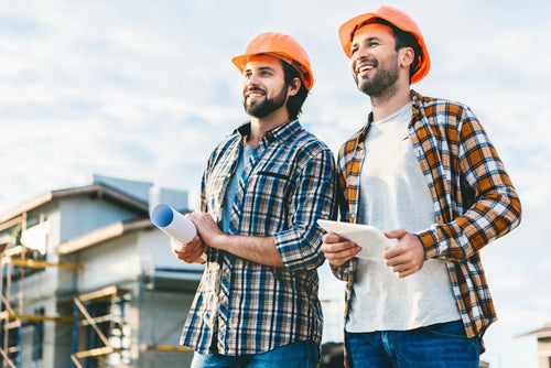 Two men in construction hats standing outdoors with a building in the background