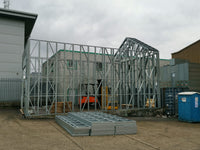 Metal framework structure under construction with a forklift in an industrial setting