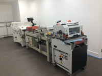Industrial paper folding machine in a room with white walls and gray floor.