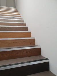 Wooden staircase with metal risers against a white wall