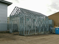 Metal frame structure on a construction site with buildings in the background
