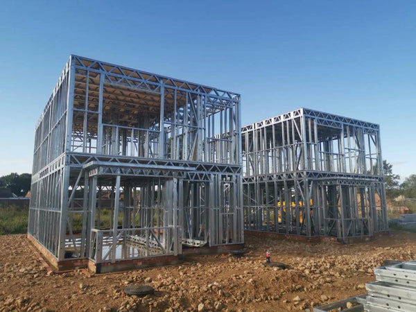 Two buildings under construction with metal frames against a clear blue sky.