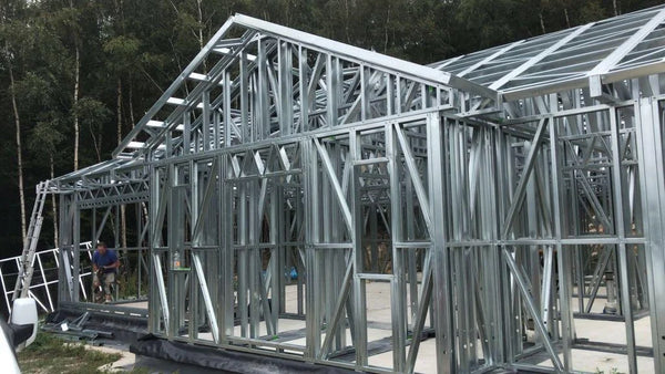Metal frame of a building under construction with trees in the background