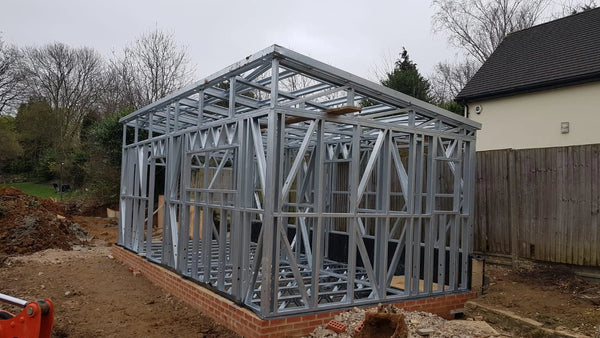 Metal frame of a building under construction in a backyard setting.